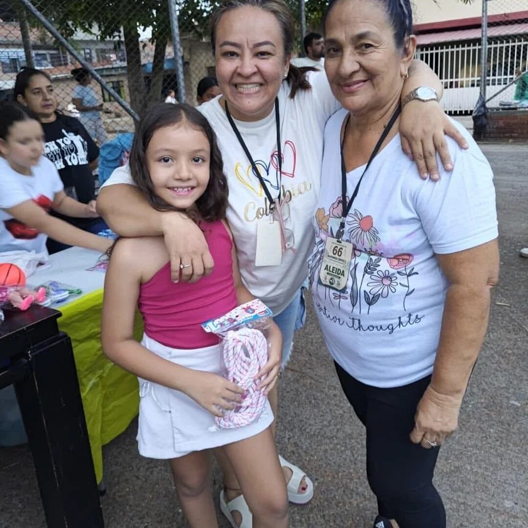 Mujeres y niña sonriendo durante jornada comunitaria